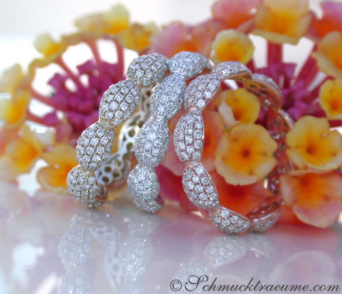 Weißgold-Brillanten-Memory-Ring mit feinem Pavé-Design, detailreich, elegant, auf Blütenblättern präsentiert.