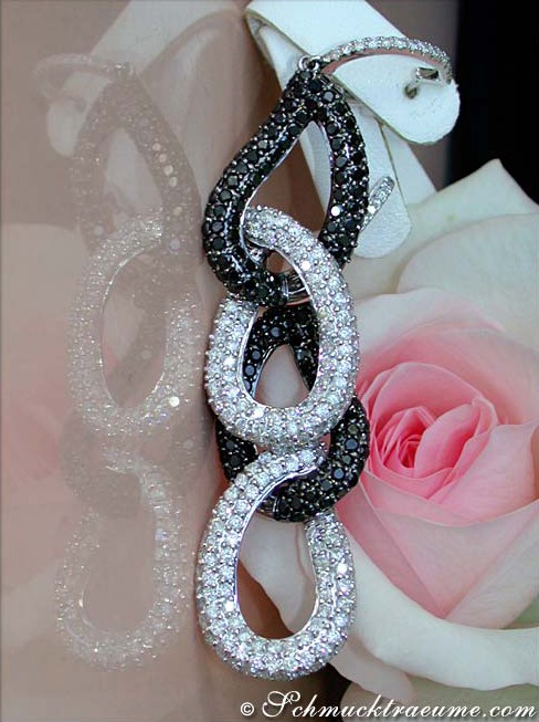 Detailliertes Ohrgehänge aus Weißgold 750 mit schwarzen und weißen Diamanten, rosa Rose im Hintergrund.
