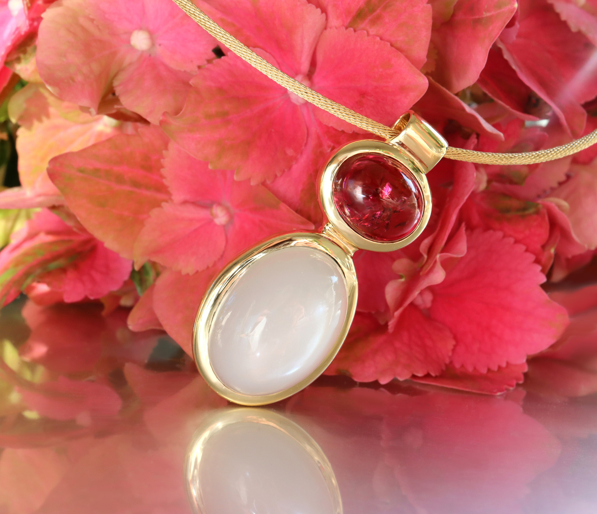 Goldene Rubellit und Mondstein Halskette auf pinken Blüten