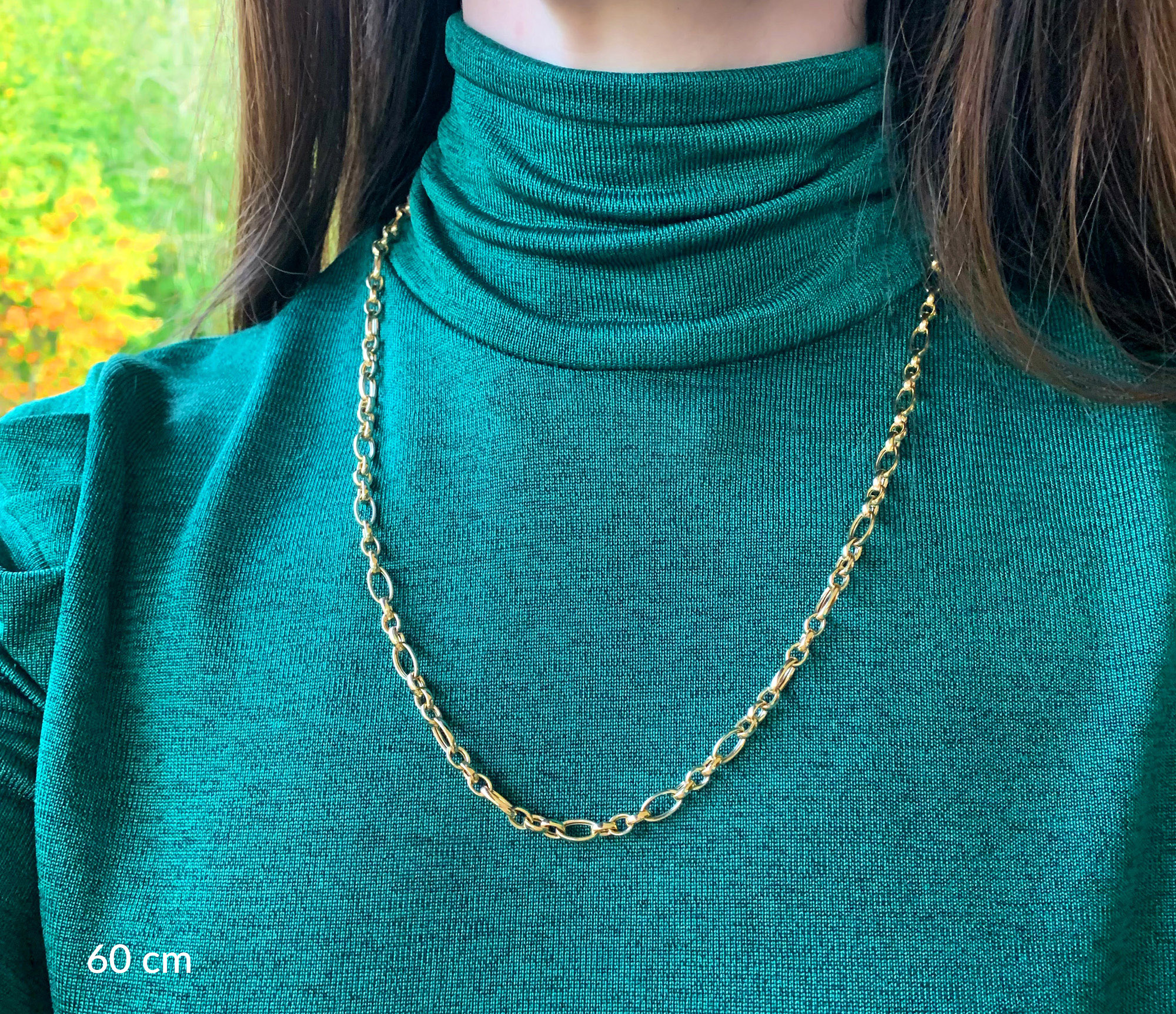 Goldkette in Gelbgold 585 mit ovalen und runden Gliedern, getragen unter grünem Rollkragenpullover.