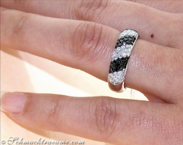Weißgold-Ring mit schwarzen und weißen Diamanten auf Handfinger.