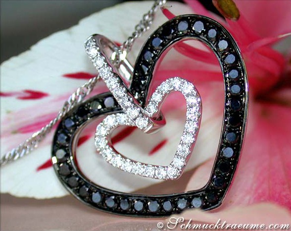 Herz-Anhänger aus Weißgold mit Diamanten und schwarzen Diamanten, Detailaufnahme auf Blume liegend