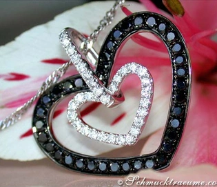 Herz-Anhänger aus Weißgold mit Diamanten und schwarzen Diamanten, Detailaufnahme auf Blume liegend
