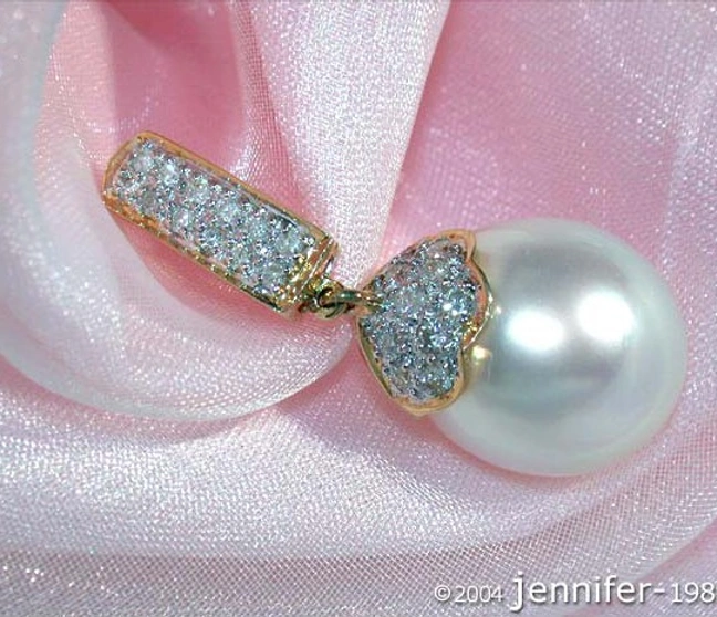 Klassischer Südseeperlenanhänger mit Brillanten in Gelbgold, Detailaufnahme auf rosa Stoff Klassischer Südseeperlenanhänger mit Brillanten in Gelbgold, Detailaufnahme auf rosa Stoff