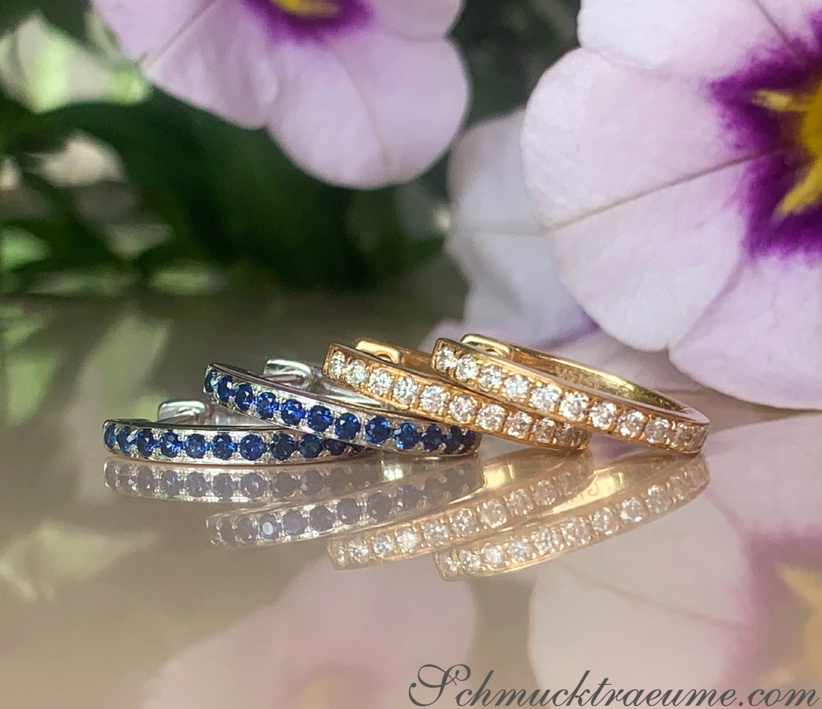 Mini Brillanten Creolen aus Gelbgold 585, detailreich gestaltet, vor blühendem Hintergrund.