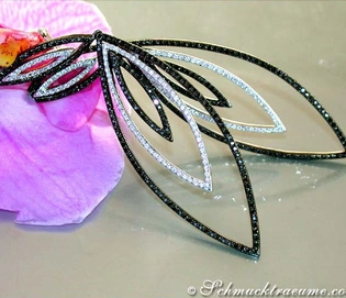 Schwarze Diamanten-Ohrringe mit weißer Verzierung, detailreich, lang, auf Blume liegend.