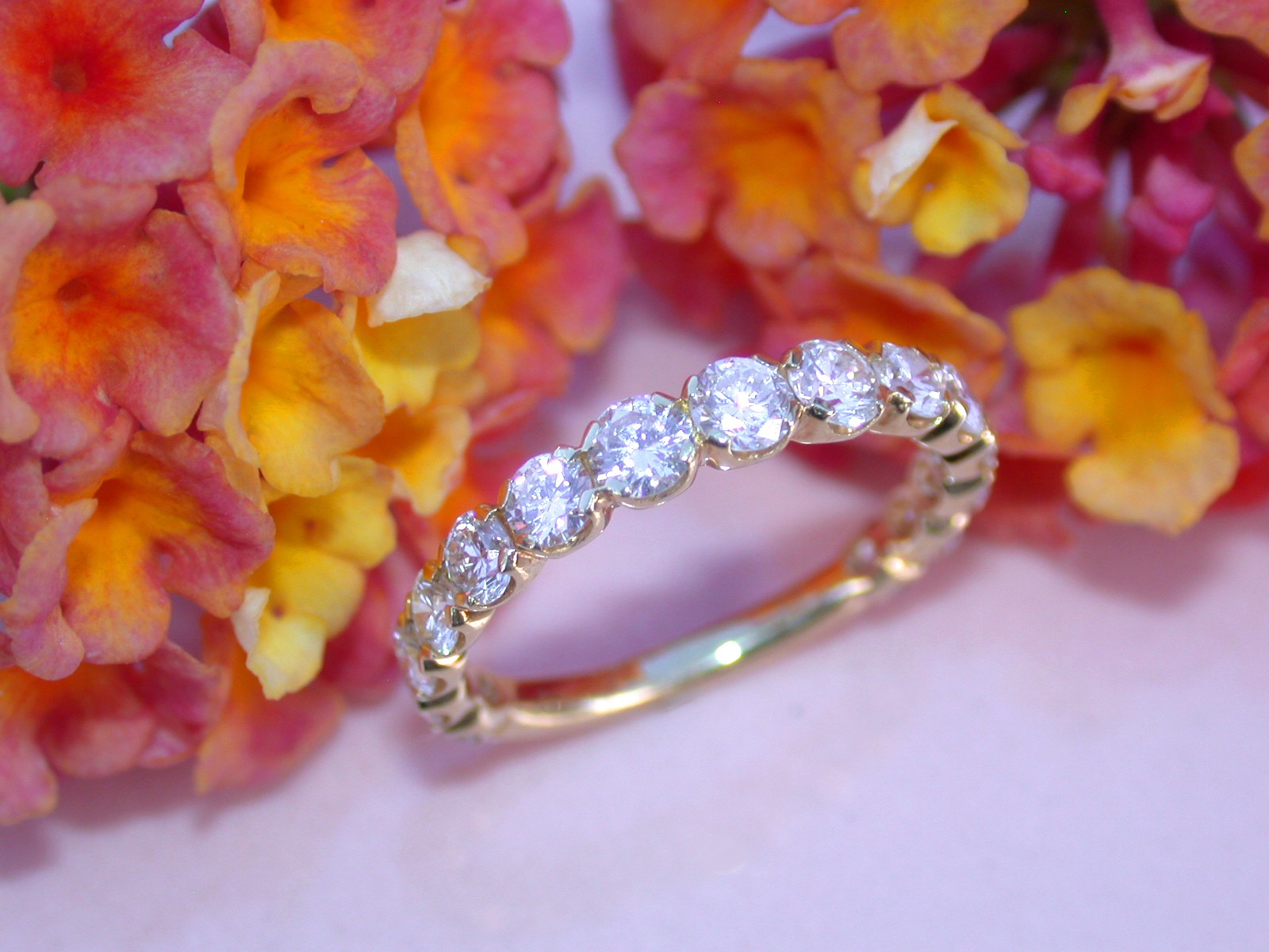 Goldener Brillant-Ring mit 14 Diamanten, Detailaufnahme auf Blütenhintergrund