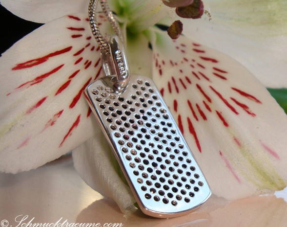 Detailaufnahme des sportlichen Dog-Tag-Anhängers mit schwarzen Diamanten auf Blüte.