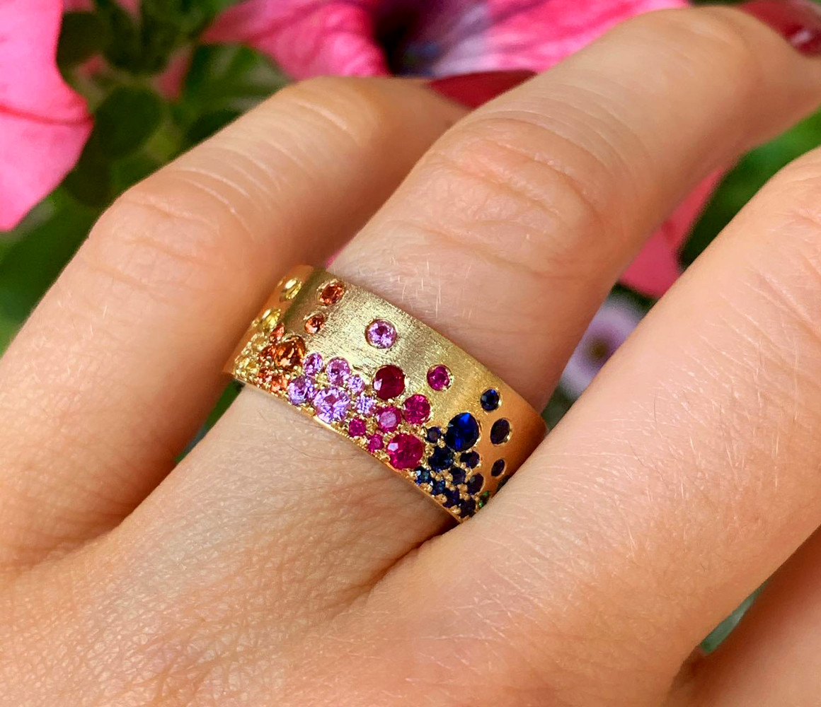 Goldener Ring mit farbigen Saphiren, Rubinen und Tsavorites auf satiniertem Gelbgold, Detailaufnahme.