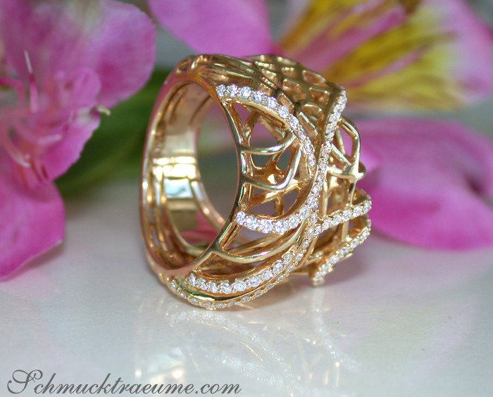 Goldener Ring mit Diamanten und Rosendesign, Detailaufnahme, Blumen im Hintergrund.