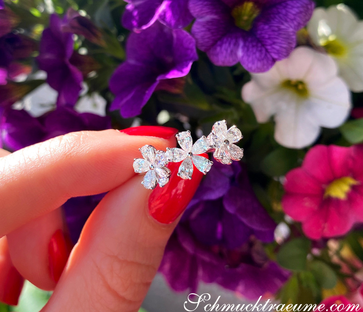 Weißgold-Ring mit Diamantblüten auf blühendem Hintergrund