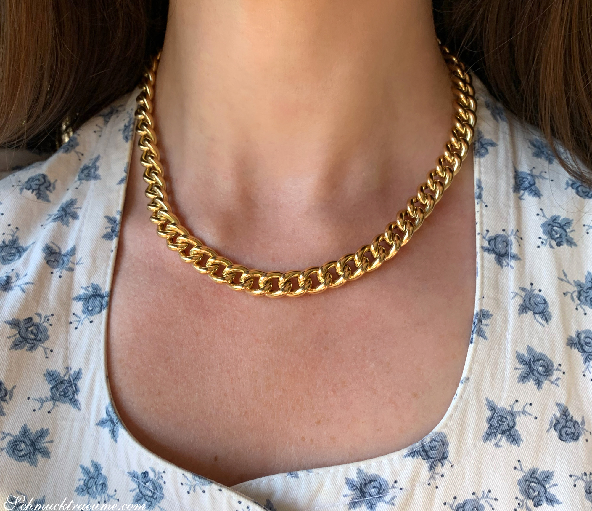 Goldene Panzerkette auf Hals von Frau in Blumenkleid