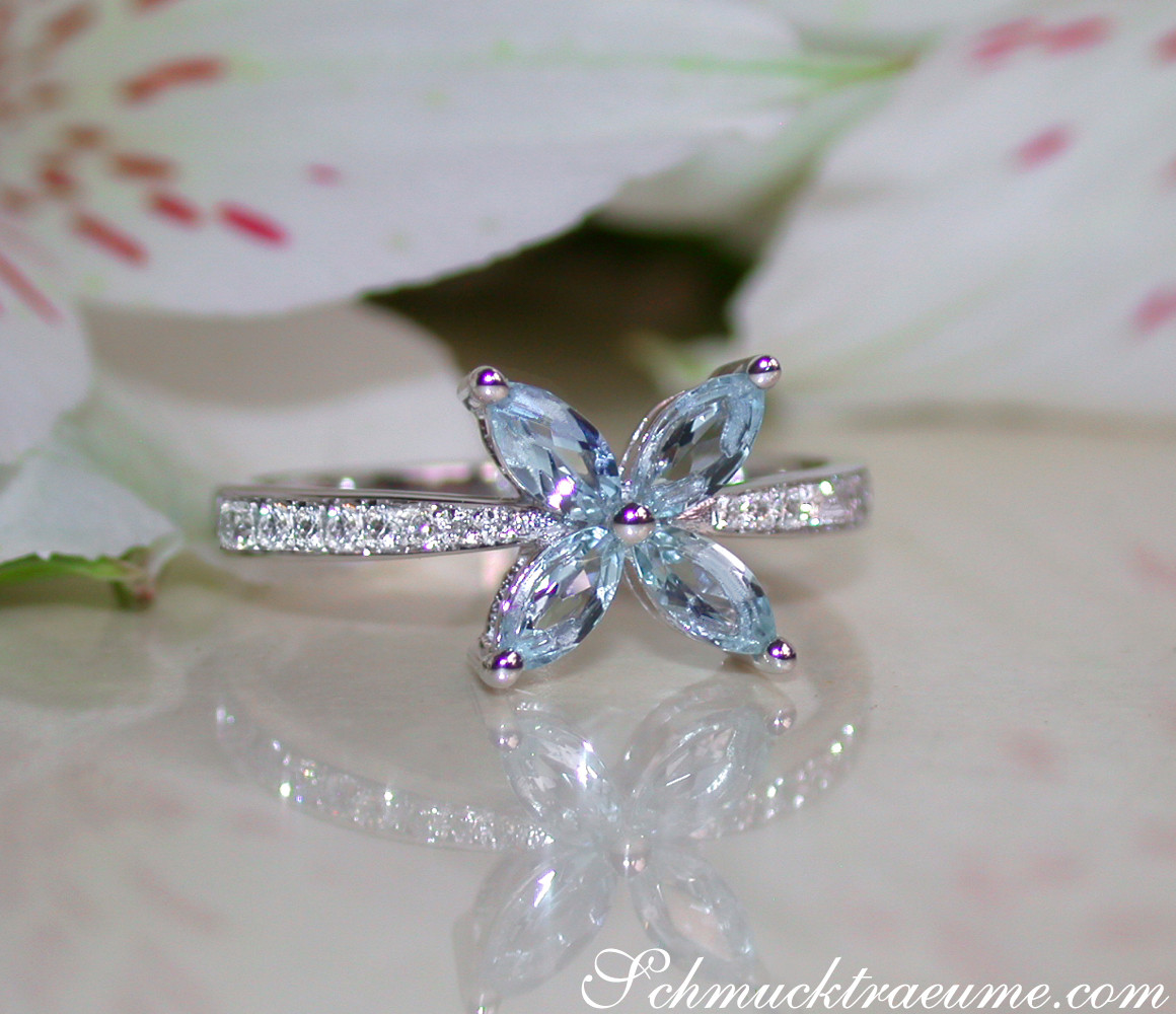 Weißgoldring mit Aquamarinen und Diamanten auf Blütenblättern.