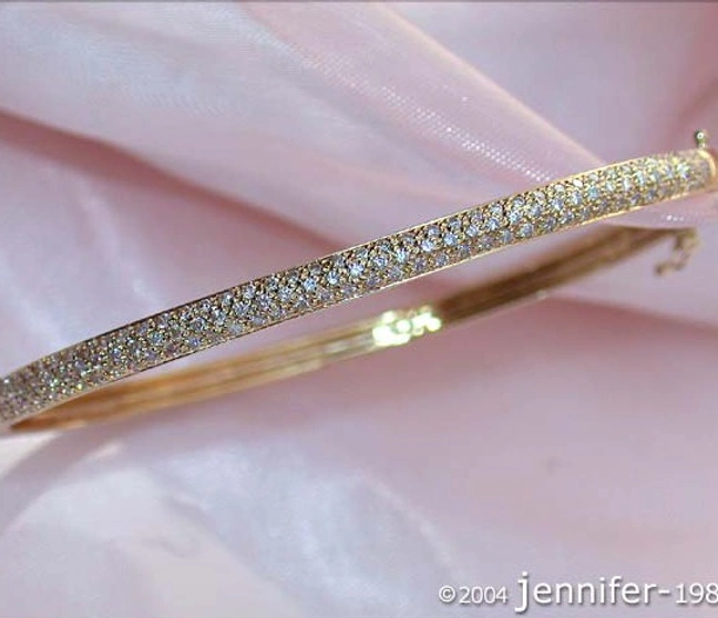 Goldener Diamantenarmreif auf rosa Stoff, Detailaufnahme Goldener Diamantenarmreif auf rosa Stoff, Detailaufnahme