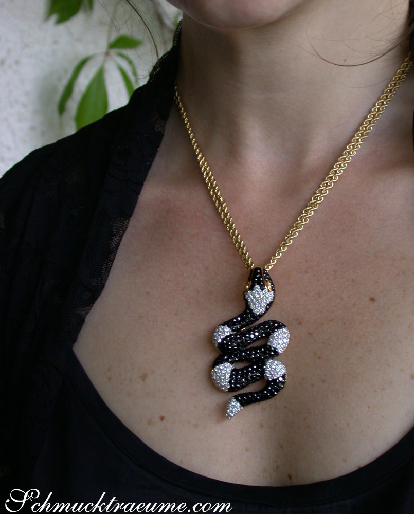 Goldkette mit schwarz-weißem Schlangenanhänger getragen