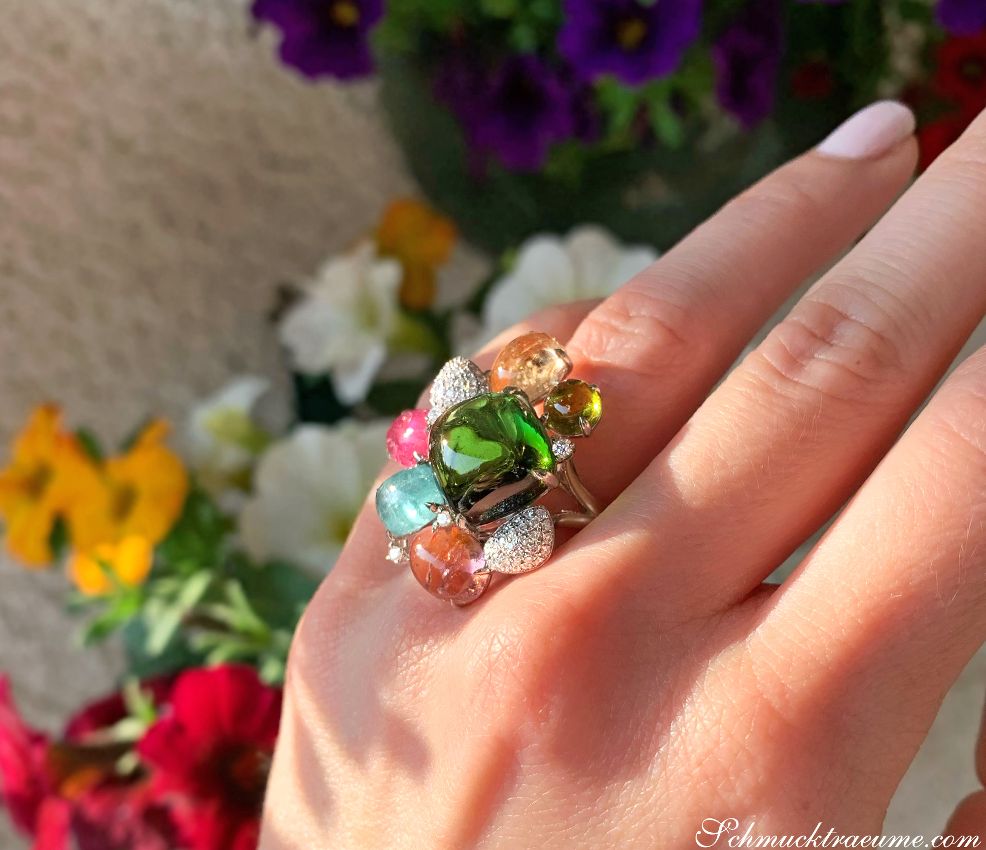 Multicolor Turmalin-Ring mit Brillanten auf Hand vor Blumen