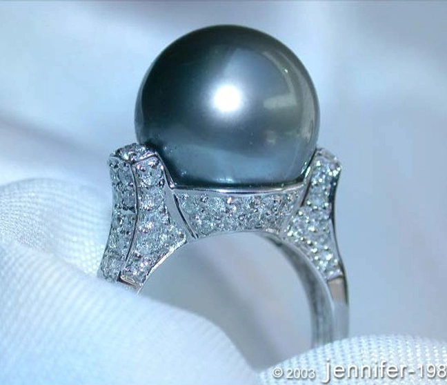 Tahitiperlenring mit Diamantkragen auf weißer Stoffoberfläche Tahitiperlenring mit Diamantkragen auf weißer Stoffoberfläche
