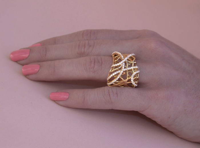Goldener Brillantenring mit feiner Struktur auf Hand mit rosa Nagellack