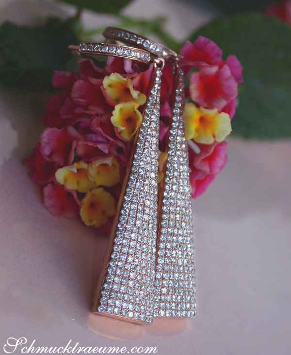 Interessante Diamanten-Ohrgehänge in Roségold, detailreich, vor Blüten im Sonnenlicht