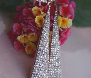 Interessante Diamanten-Ohrgehänge in Roségold, detailreich, vor Blüten im Sonnenlicht