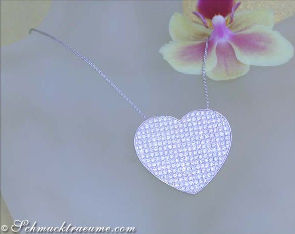 Herzförmiges Diamantcollier mit weißgoldener Kette, zarte Orchidee im Hintergrund