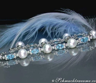 Süßwasserperlen-Armband mit Blautopasen und Brillanten, detailreich, Feder im Hintergrund.