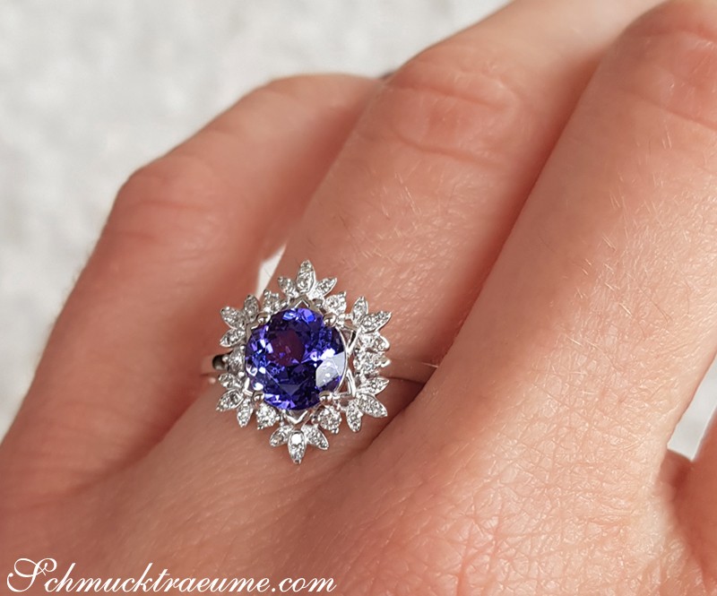 Weißgold-Tanzanit-Ring mit Diamanten im Blütenkranz-Design auf Handfinger.