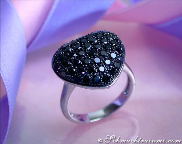 Herzring mit schwarzen Diamanten auf weißgoldener Basis, Detailaufnahme, elegant getragen.