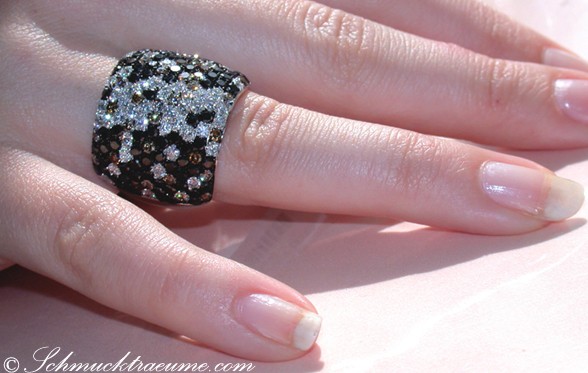 Schwarz-weiß-brauner Diamant-Ring auf Hand, Detailaufnahme.