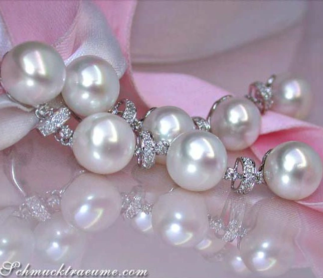 Edle Süßwasserperlen-Ohrringe mit Diamanten auf rosa Seide Edle Süßwasserperlen-Ohrringe mit Diamanten auf rosa Seide