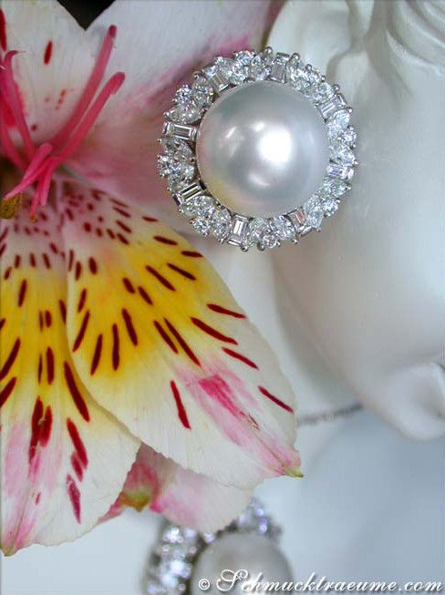 Weißgoldohrringe mit Südseeperlen und Diamanten, Detailaufnahme, Blume im Hintergrund