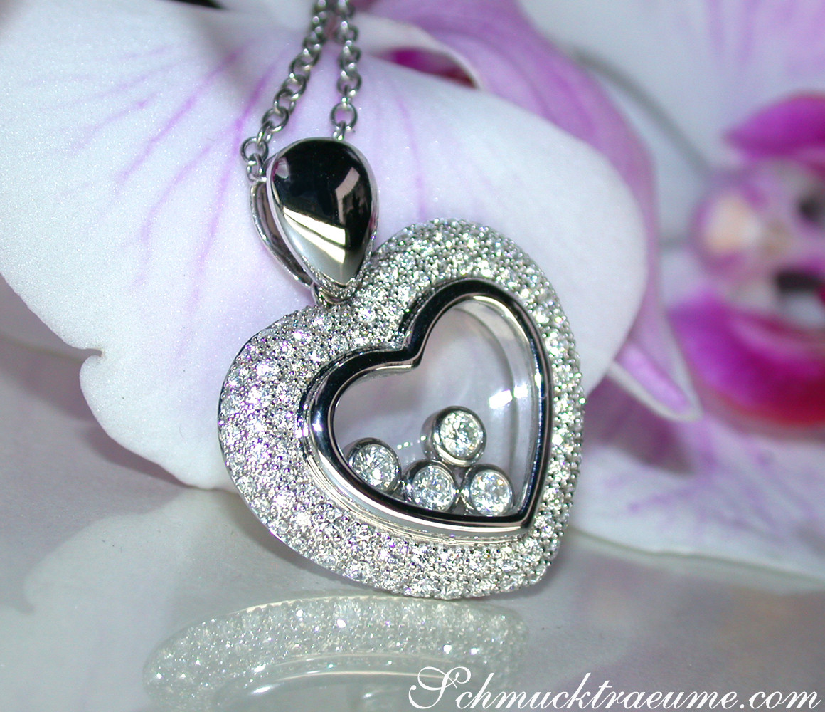 Herz-Anhänger mit Brillanten im Brillant-Herz, Detailaufnahme, zarte Kette, Orchideenblüte im Hintergrund