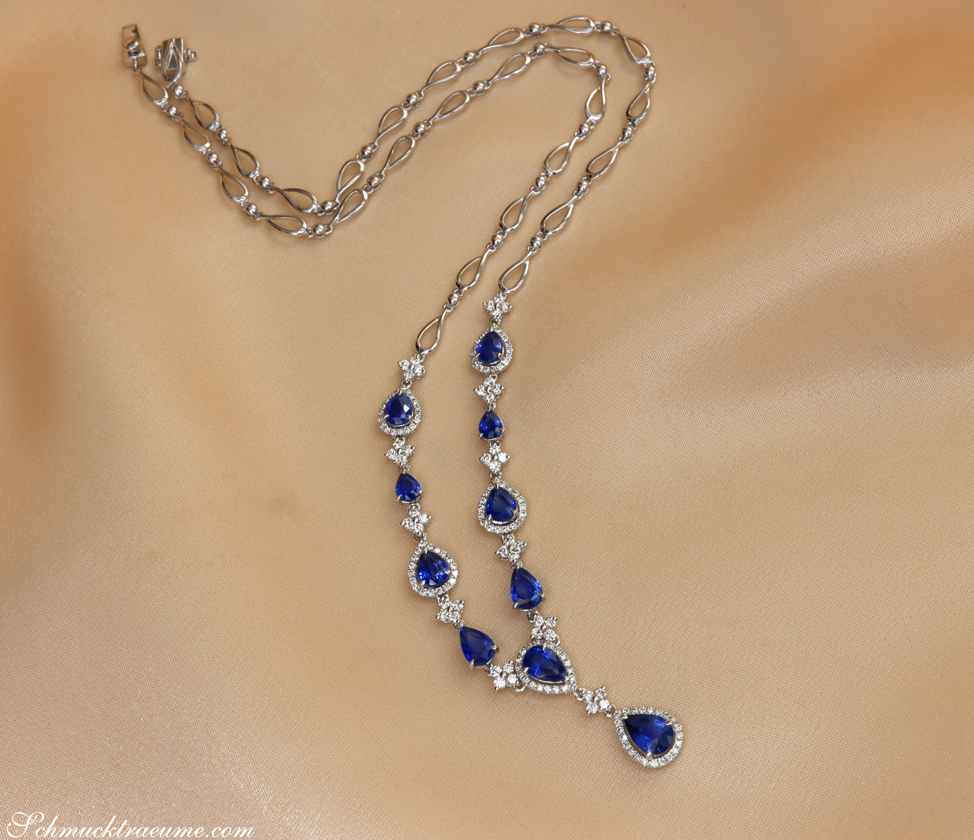 Silbernes Saphir-Collier mit Brillanten auf cremefarbener Stoffoberfläche