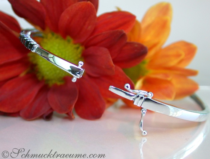 Schwarzer Diamant-Armreif in Weißgold, Detailaufnahme mit Blume im Hintergrund