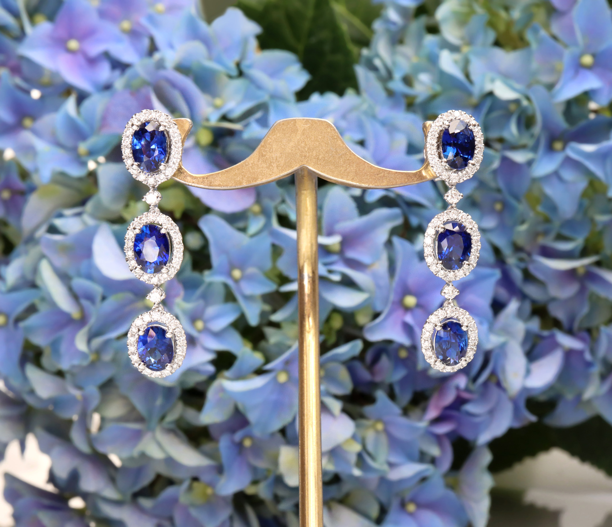 Blauer Saphir-Ohrhänger mit Brillanten, elegant auf Blütenhintergrund präsentiert