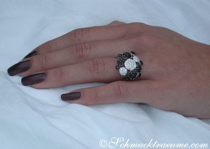 Schwarz-weißer Diamant-Ring auf Hand mit dunklem Nagellack