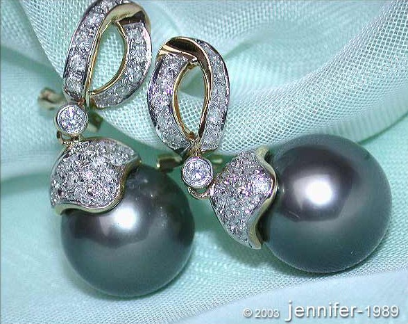 Detail der eleganten Tahitiperlen-Ohrringe mit Diamanten in Gelbgold, vor grünem Hintergrund.