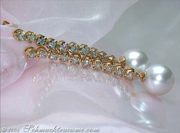 Goldene Perlenohrringe mit Brillanten auf weißem Stoff, Detailaufnahme