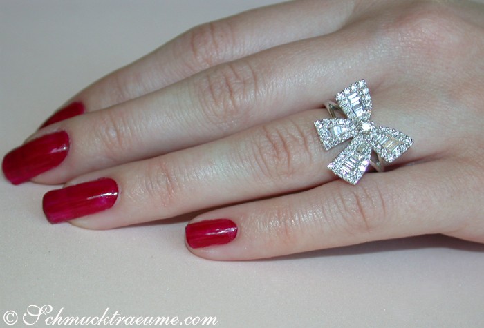 Femininer Diamanten-Schleifen-Ring auf Hand mit rotem Nagellack