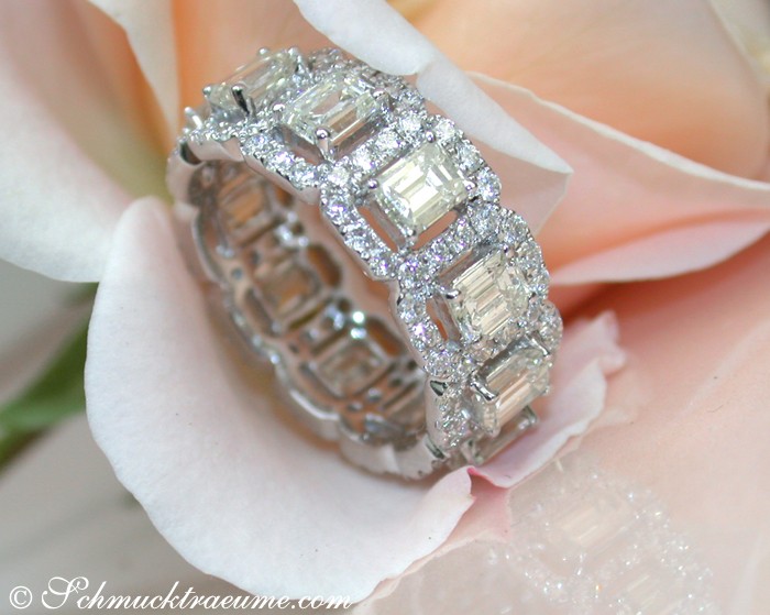 Weißgoldring mit 11 Smaragdschliff-Diamanten, detailreich, auf Rosenblüte gelegen.