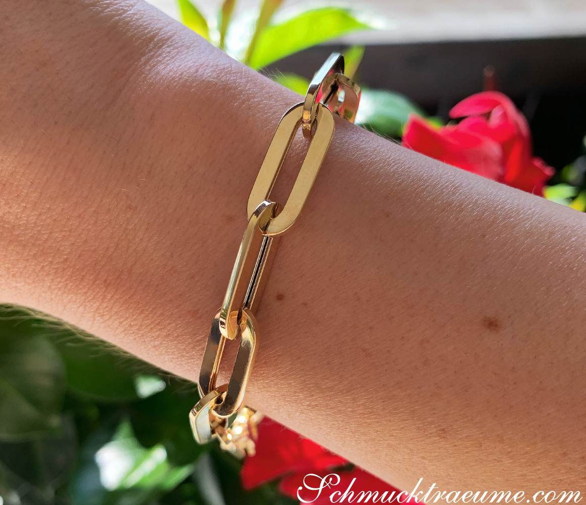 Gold-Papierclip-Armband in Gelbgold 585, Detailaufnahme am Handgelenk, Pflanzen im Hintergrund