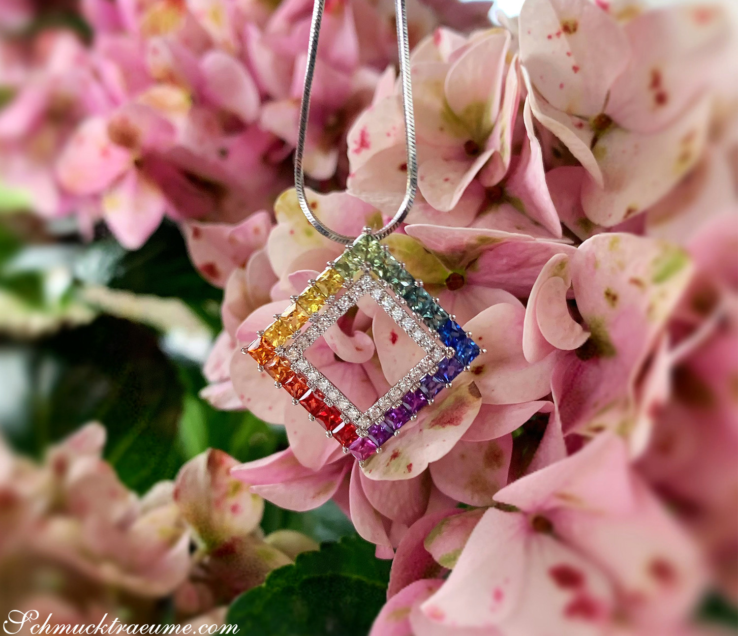 Regenbogen-Saphir-Anhänger mit Brillanten in Weißgold, Detailaufnahme, hängend auf Hortensienblüten.