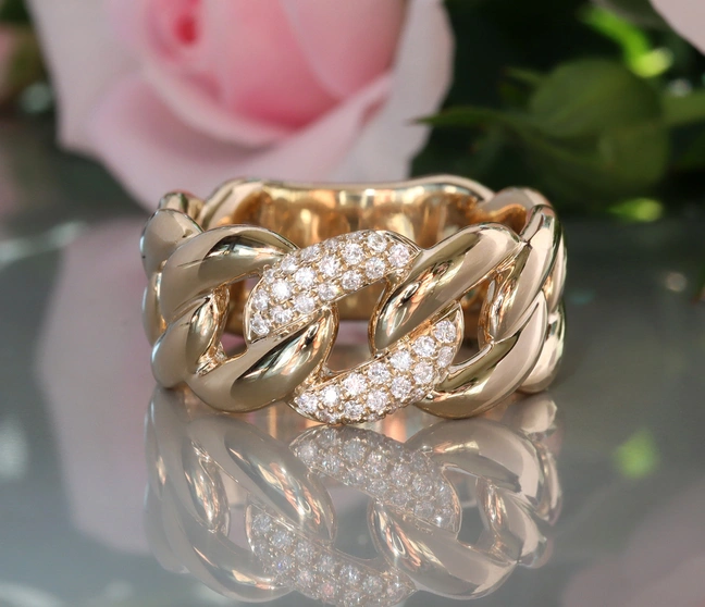 Goldener Panzerketterring mit Brillanten auf glänzender Oberfläche Goldener Panzerketterring mit Brillanten auf glänzender Oberfläche