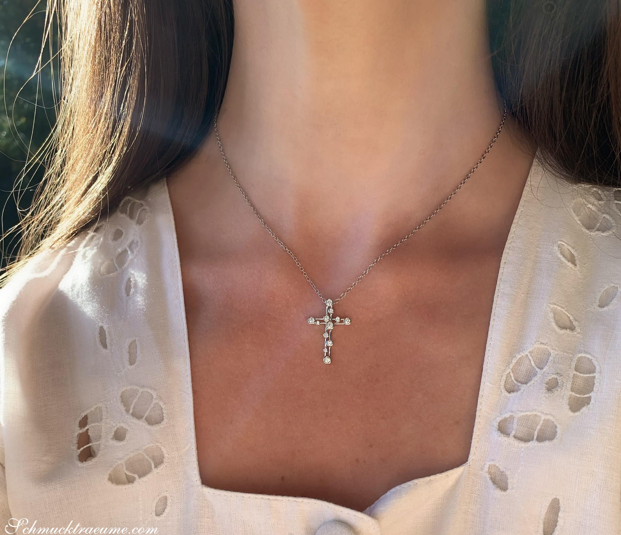 Klassischer Kreuzanhänger mit Brillanten auf Halskette, getragen unter weißem Oberteil
