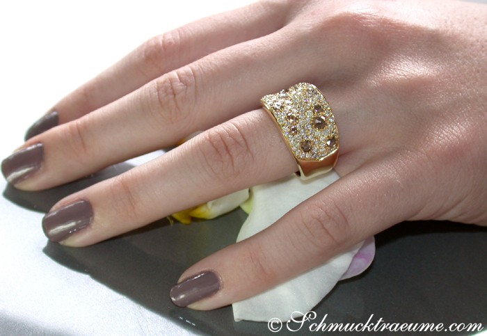 Goldener Brillant-Ring mit feinen weißen und naturbraunen Steinen, Detailaufnahme, elegant getragen.