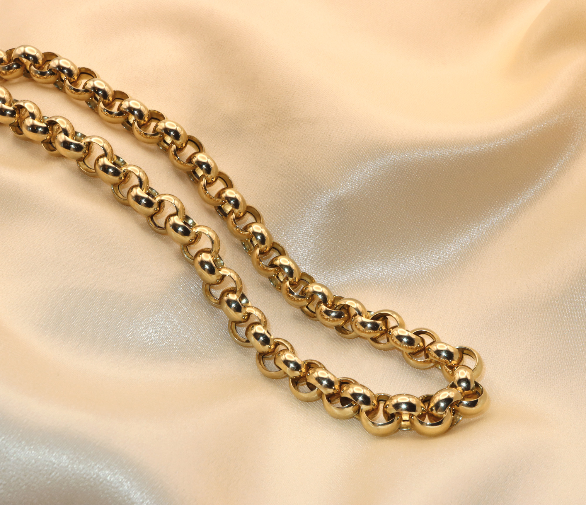 Goldkette aus Gelbgold 585, glänzende Rundringe, auf cremefarbenem Stoff liegend