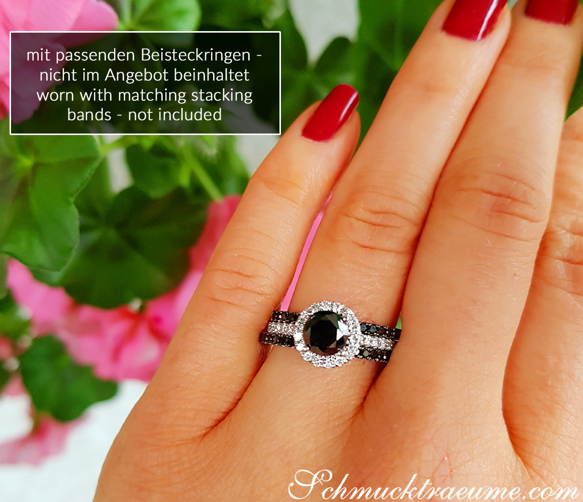 Schwarzer Diamant Solitär-Ring mit Brillanten in Weißgold, Detailaufnahme auf Hand mit roten Nägeln, Blüten im Hintergrund.