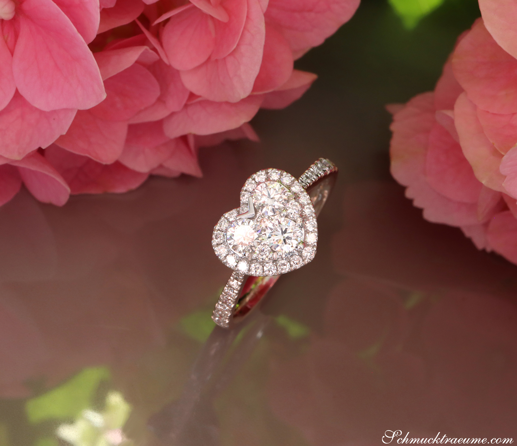 Herzformiger Diamant-Ring auf rosa Blütenhintergrund