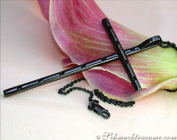 Schwarzer Diamant-Kreuz-Anhänger mit Kette, Detailaufnahme auf Blume liegend