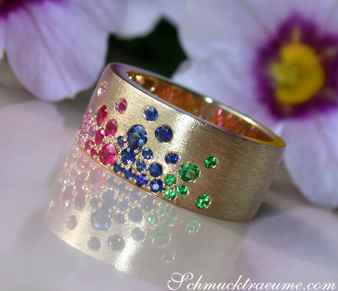 Gelbgold-Ring mit farbigen Saphiren, Rubinen und Tsavorites, Detailaufnahme, floraler Hintergrund